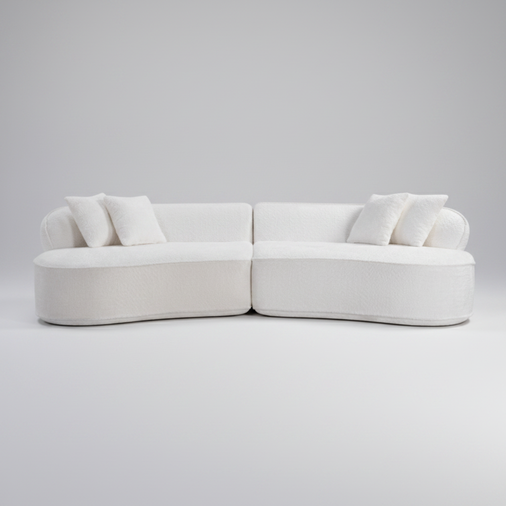 A modern curved modular sofa upholstered in off-white textured fabric, featuring two matching throw pillows, shown against a solid white background.